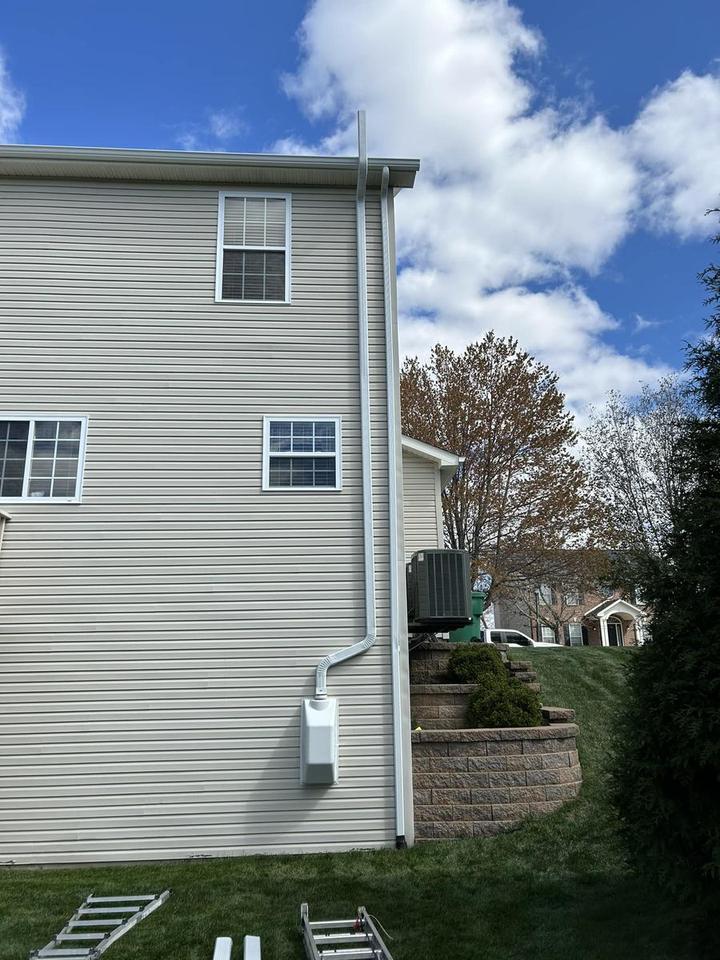 Exterior radon mitigation vent pipe and fan running up the side of a St. Louis area home