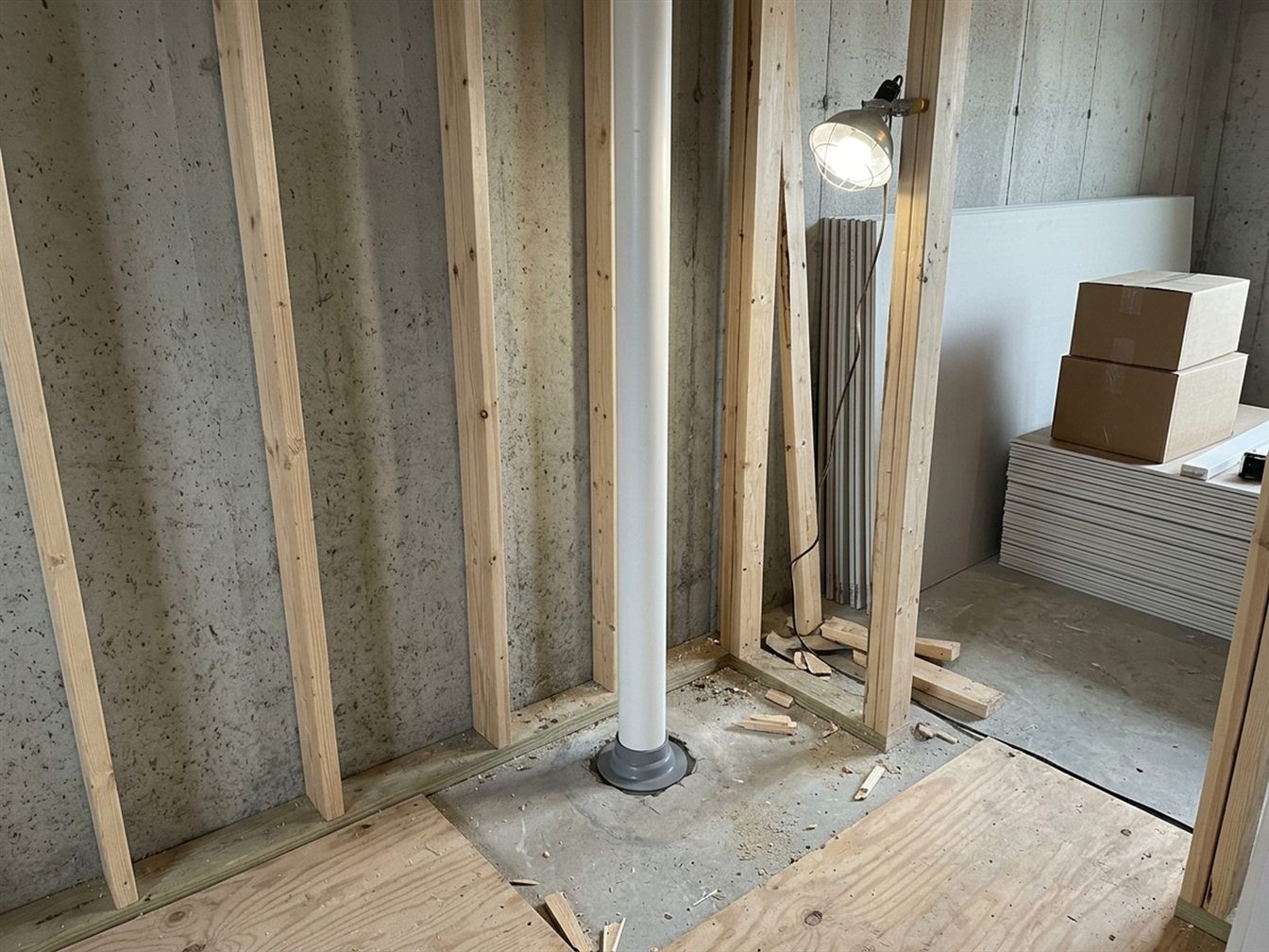 Basement being finished with new wall framing around a sealed radon mitigation pipe